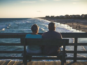 Couple sitting on bench looking at ocean who save with retirement insurance
